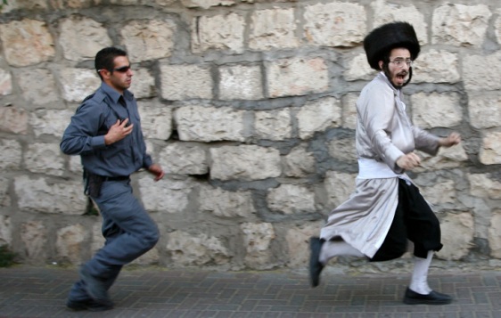 An Israeli policeman chase an Ultra Orthodox Jew who have refused to obey orders. 