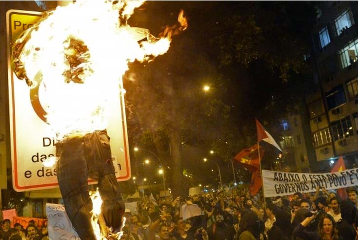 Angry protestors burn an effigy of the Pope, claiming waist of public money as reason.