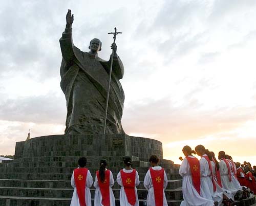 Children pray at the statue of the late Pope John Paul II in Tasitolu, Dili, East Timor 