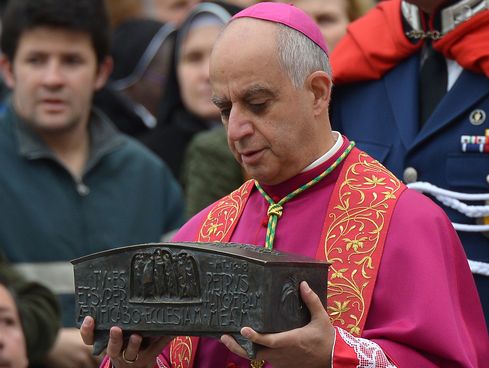 Italian archbishop Rino Fisichella holds the ashes of Saint Peter before a ceremony at the Vatican, on November 24, 2013.