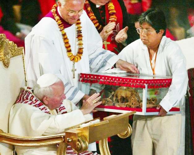 The late Pope reaches out to a Mexican skull, and wants to bless it. 