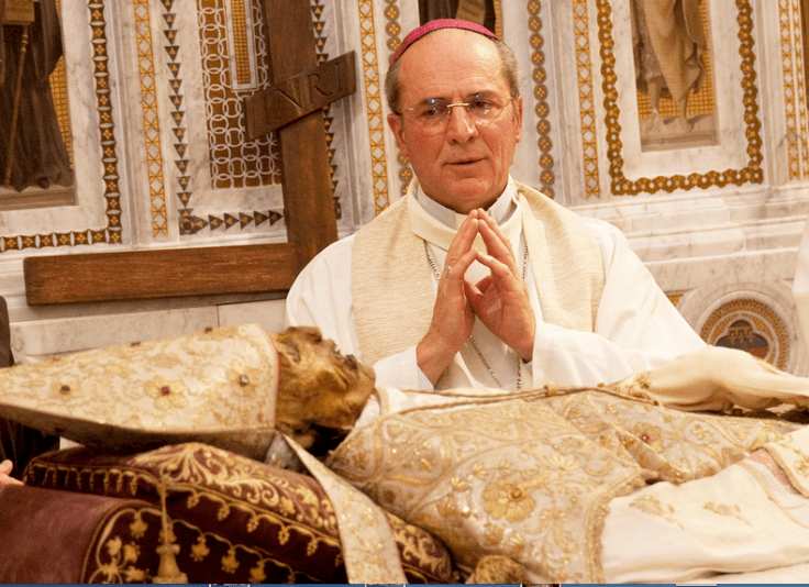A Roman Catholic priest pray and worship an front of a corpse inside a Church in Italy.